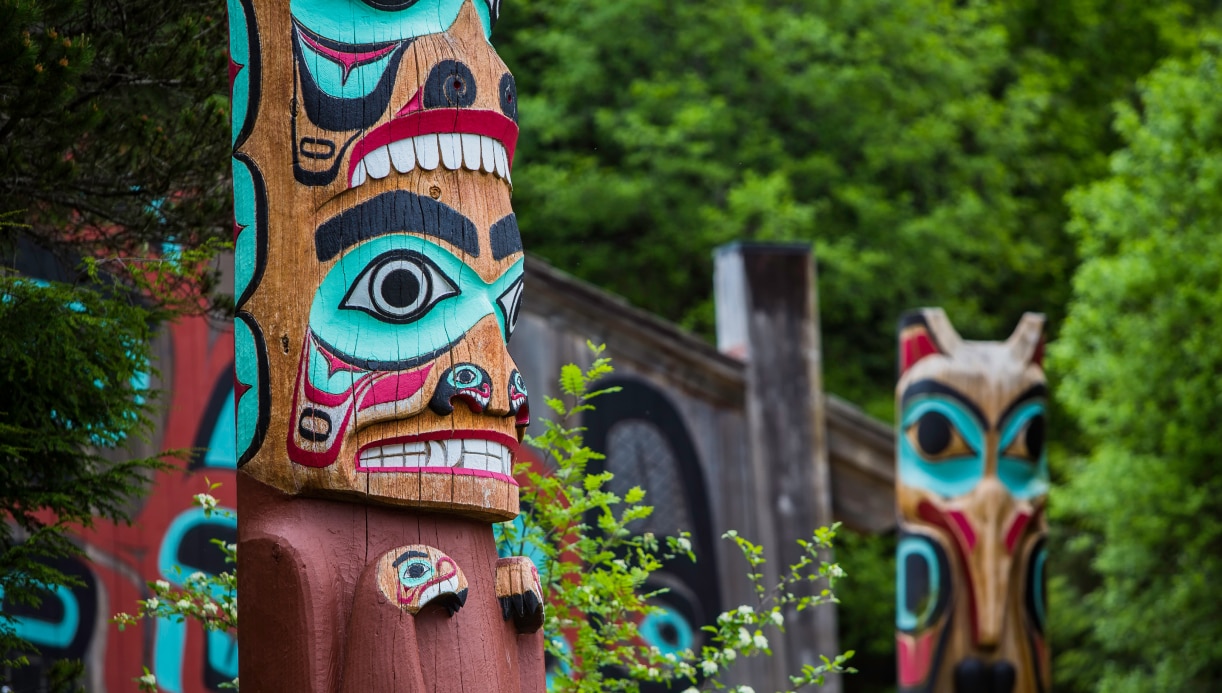 Native Alaskan totem poles situated in a wooded area of Ketchikan in Alaska.