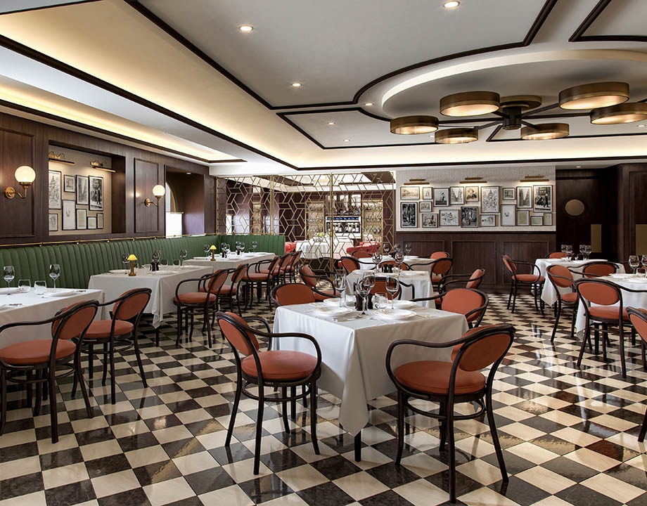 Elegant onboard restaurant with checkered flooring, white tablecloths, and warm lighting | MSC Cruises