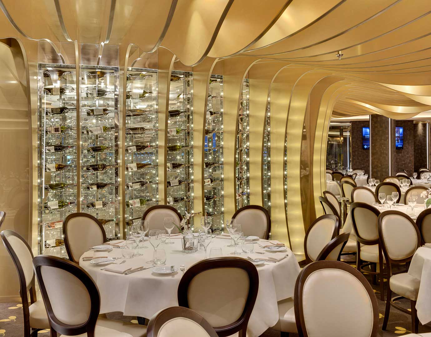 Elegant cruise ship dining room with golden decor and wine display | MSC Cruises