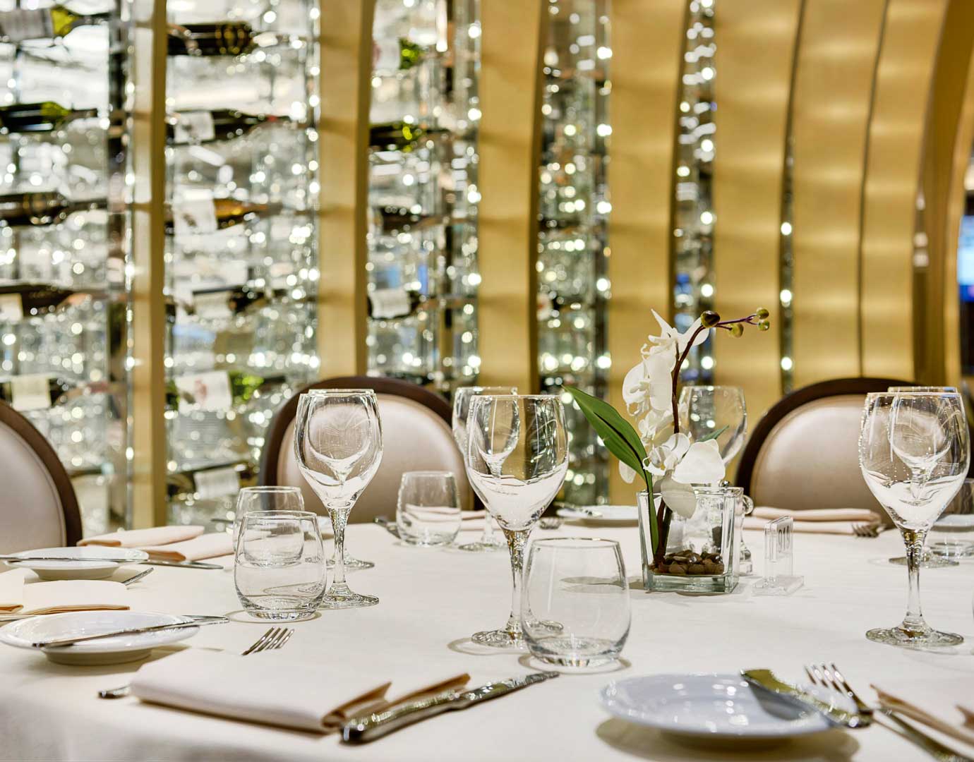 Elegant dining table with wine glasses and orchid centerpiece in a luxurious cruise setting | MSC Cruises