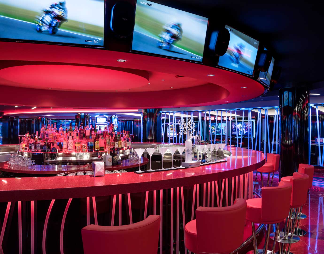 A vibrant cruise ship bar with red seating and illuminated liquor display | MSC Cruises
