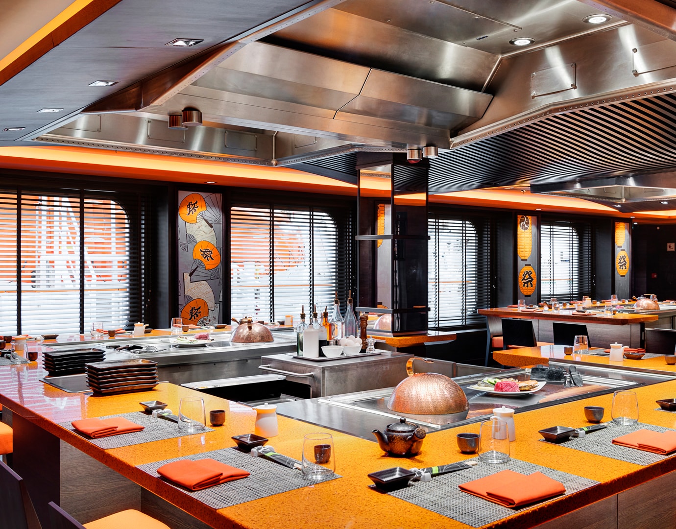 Teppanyaki-style dining area with vibrant orange decor and table settings onboard | MSC Cruises