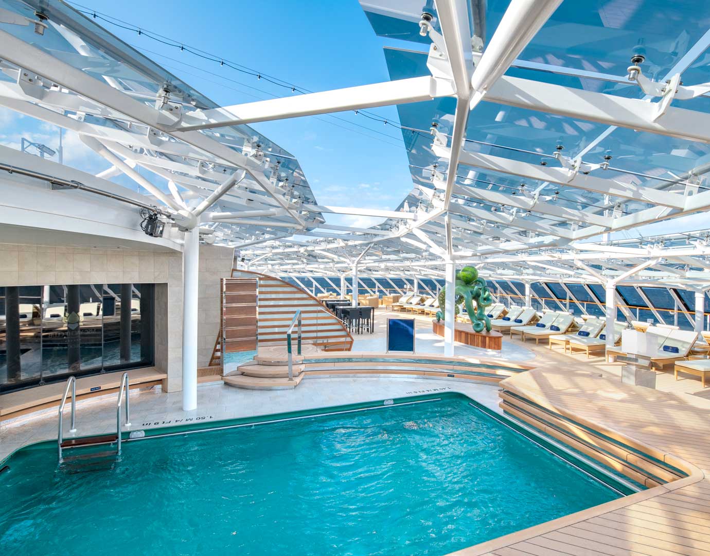 A modern cruise ship pool deck with sun loungers and a glass canopy | MSC Cruises