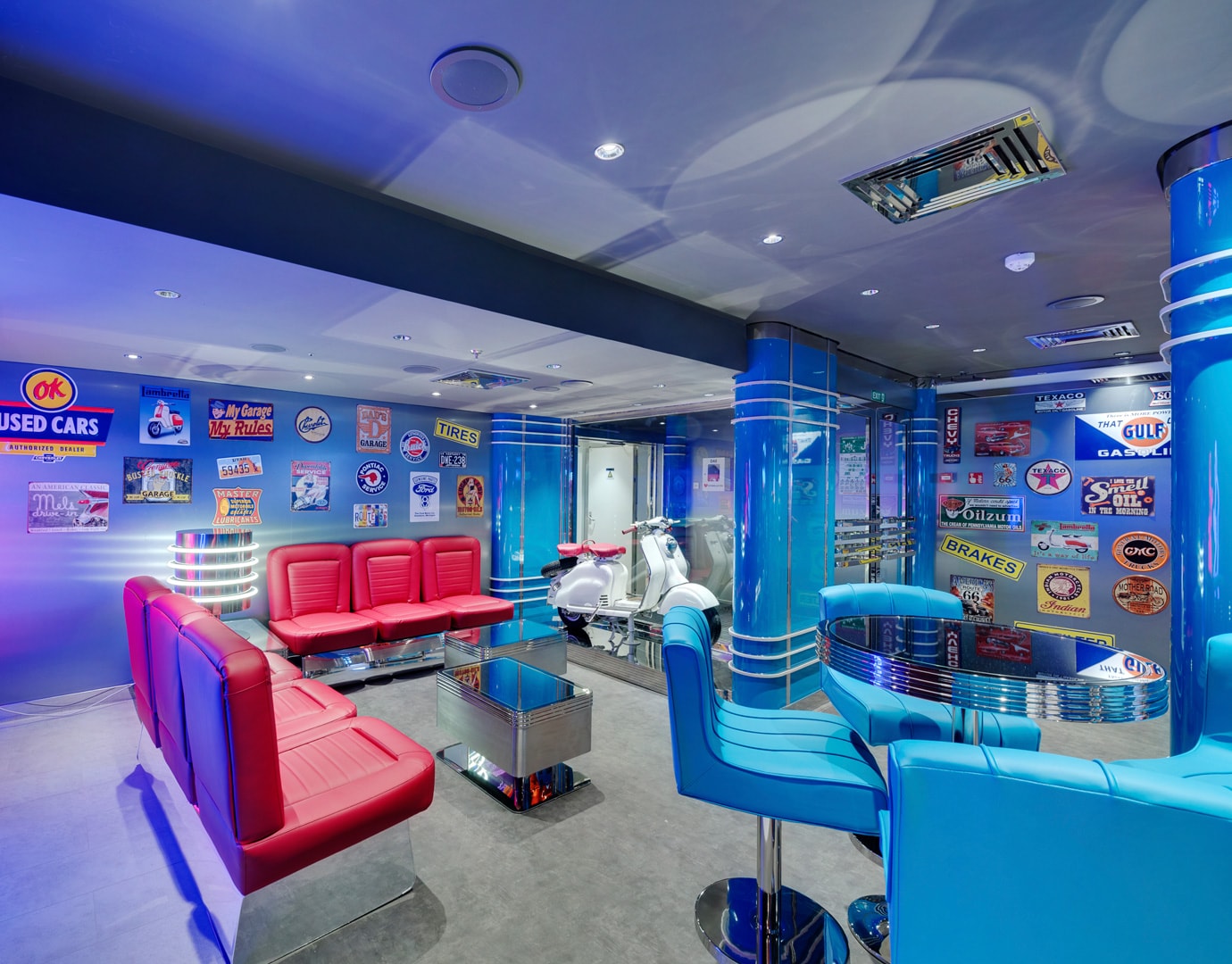 Retro-themed lounge with red and blue seating, vintage signs, and a white scooter on display | MSC Cruises