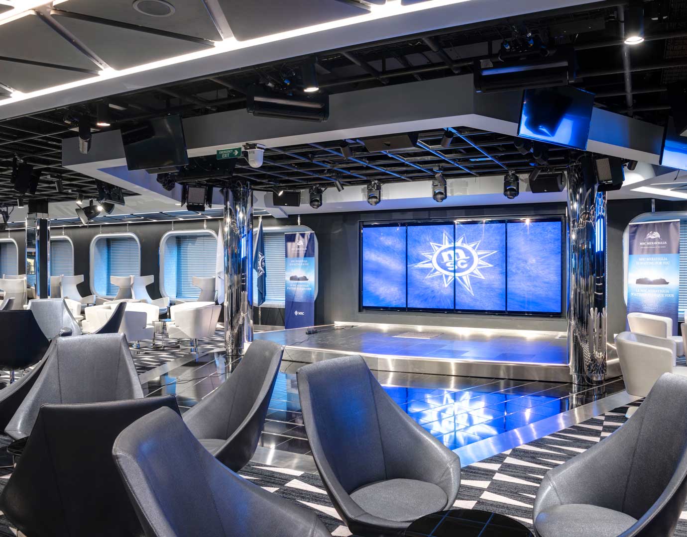 Modern lounge with sleek seating and a stage featuring the MSC logo | MSC Cruises